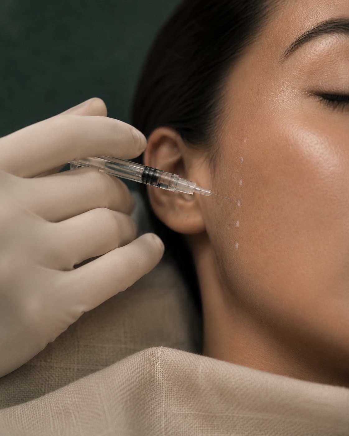 A practitioner working close to a client's cheek with a fine syringe